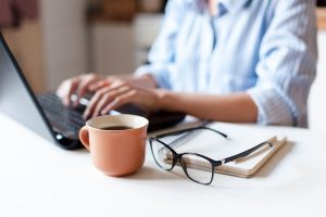 Remote working from home. Freelancer workplace in kitchen with laptop, cup of coffee, spectacles. 