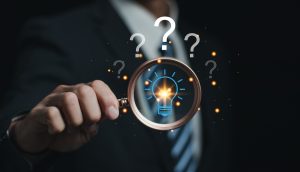 business person holding magnifying glass, surrounded by question marks. concept questioning how to choose document management software.